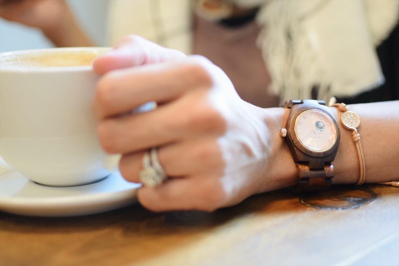 girl drinking coffee with wooden watch on