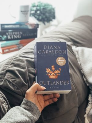 image of a hand holding a book called Outlander by Diana Gabaldon 