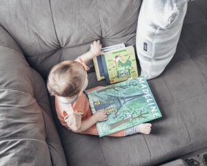 image of an infant sitting on a couch reading a book called Madeline
