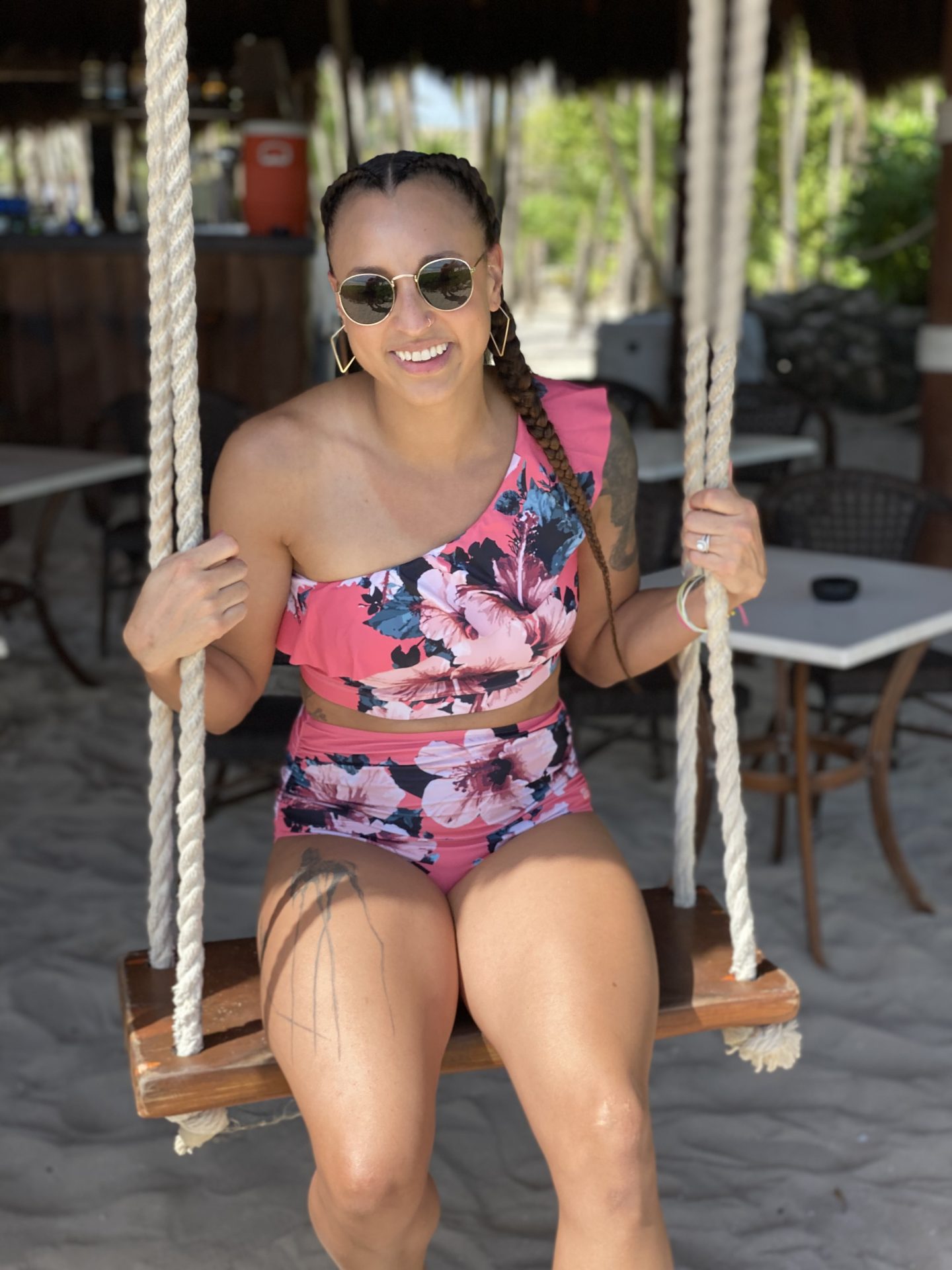 mixed race female wearing a two-piece swim suit, sitting on a swing. 