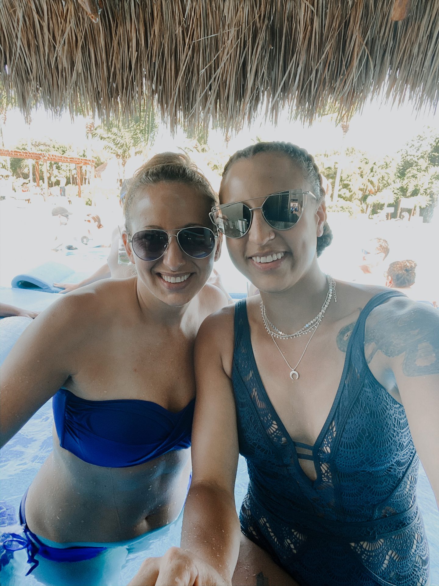 image of two women smiling, both wearing blue swimsuits next to a pool.