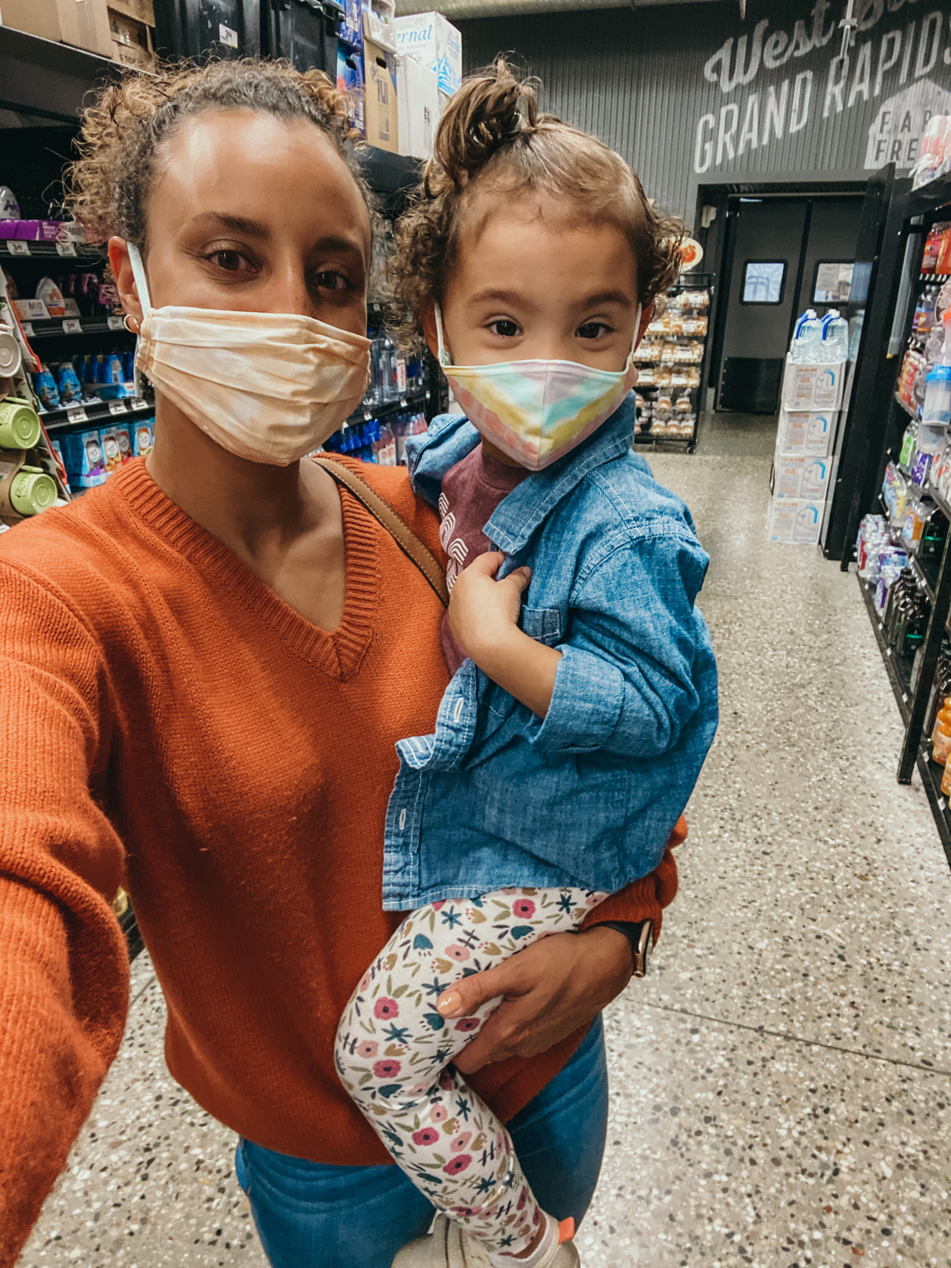 mixed race woman wearing face mask, with toddler also wearing a face mask
